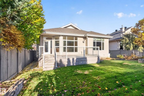 Rear exterior featuring lap siding, an elevated deck with glass railing, large picture windows, and a fenced yard - 876 Twin Brooks Close Nw, Edmonton, AB 