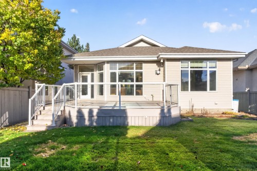 Rear exterior featuring a raised deck with glass panel railings and stairs, large multi-pane windows, and vinyl siding - 876 Twin Brooks Close Nw, Edmonton, AB 