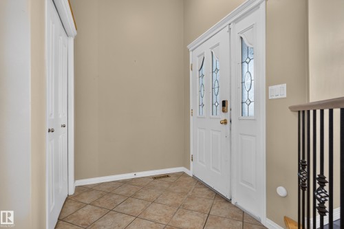 Double-door entry featuring decorative glass inserts, high ceilings, tile flooring, and metal baluster railing - 876 Twin Brooks Close Nw, Edmonton, AB 