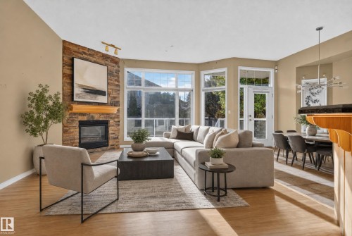 Stacked stone fireplace with a wood mantel, wood-finish flooring, floor-to-ceiling windows, and glass-paned exterior door - 876 Twin Brooks Close Nw, Edmonton, AB 