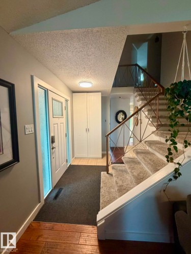 Entryway featuring wood-finish flooring, a white paneled entry door with frosted sidelight, and built-in white cabinetry - 5 Gilmore Crescent, St. Albert, AB 