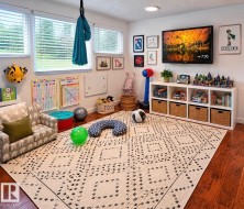 Recessed lighting, large windows with white blinds, wood-finish flooring, and a built-in shelving unit with cubbies - 