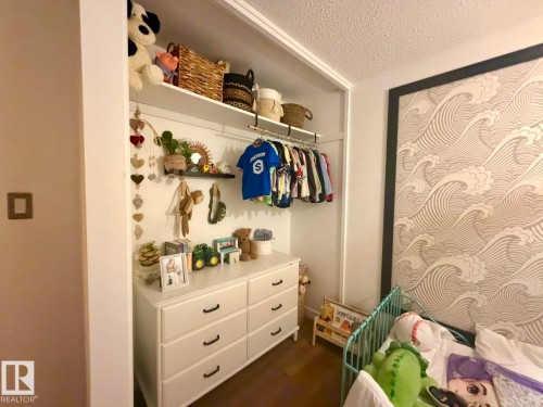 Built-in closet system with open shelving and clothing rod, white six-drawer dresser with black hardware, and patterned accent wall - 5 Gilmore Crescent, St. Albert, AB 