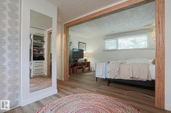 Wood-finish flooring, full-length mirror, built-in closet organization, and wood-framed doorway - 