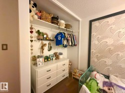 Built-in closet system with open shelving and clothing rod, white six-drawer dresser with black hardware, and patterned accent wall - 