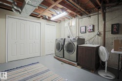 Dedicated laundry area featuring a utility sink and cabinetry, two bi-fold doors, and exposed ceiling joists - 