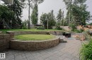 Expansive backyard featuring a stone paver patio, multi-level stone retaining walls, and mature perimeter trees - 5 Gilmore Crescent, St. Albert, AB 
