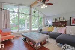 Vaulted ceiling with exposed wood beam, wood-finish flooring, large windows, and ceiling fan with integrated lighting - 