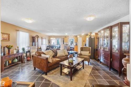 Spacious open-concept living area featuring large-format tile flooring set on a diagonal, neutral wall tones, and recessed ceiling lighting - 497 Kananaskis Drive, Devon, AB 