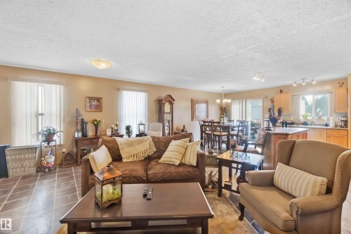 Open-concept interior featuring large-format tile flooring, recessed and flush-mount lighting, and kitchen cabinetry with a wood finish - 497 Kananaskis Drive, Devon, AB 