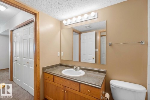 Virtually Decluttered- Bathroom featuring a wooden vanity, integrated countertop with a white oval sink, wall-mounted mirror, and multi-bulb light fixture - 497 Kananaskis Drive, Devon, AB 