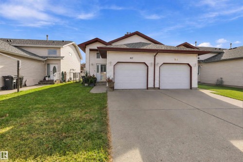 Multi-level residence featuring horizontal vinyl siding, dual-car garage, concrete driveway, and asphalt shingle roof - 497 Kananaskis Drive, Devon, AB 
