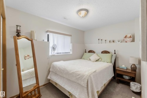 Neutral-toned room featuring wall-to-wall carpeting, recessed architectural display ledge, horizontal window with integrated blinds, and flush-mount ceiling lighting - 497 Kananaskis Drive, Devon, AB 