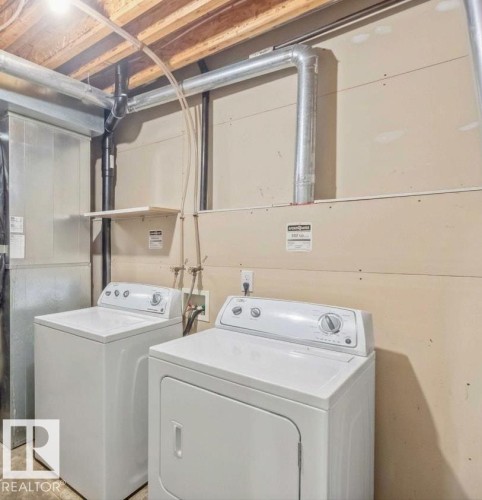 Utility area featuring an upright water heater, forced-air furnace unit, exposed ceiling joists, and designated laundry hookups - 497 Kananaskis Drive, Devon, AB 