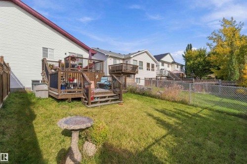 Multi-level wood deck featuring integrated railings and stair access, chain-link perimeter fencing, and a grass lawn - 497 Kananaskis Drive, Devon, AB 