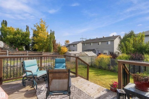 Elevated wood deck featuring vertical baluster railings, overlooking a fenced backyard with established landscaping - 497 Kananaskis Drive, Devon, AB 