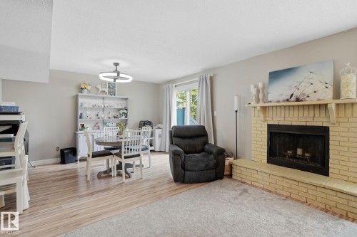 Brick fireplace with hearth, wood-finish flooring, sliding glass door, and recessed lighting - 5340 38A Avenue Nw, Edmonton, AB 