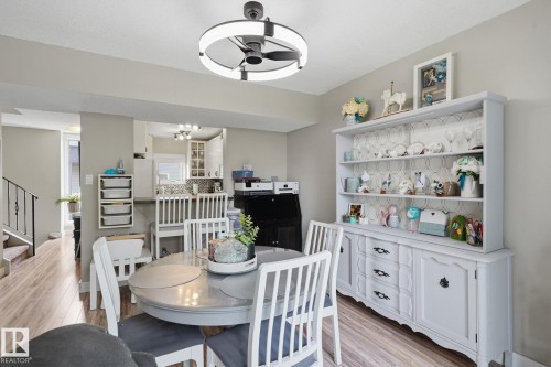Wood-finish flooring throughout, modern ceiling fan with integrated lighting, built-in display hutch with shelving, and staircase with metal railing - 5340 38A Avenue Nw, Edmonton, AB 