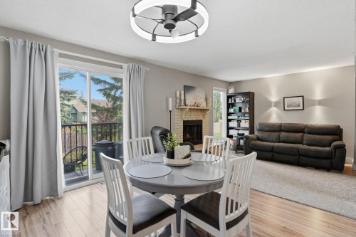 Wood-finish flooring, sliding glass doors to outdoor balcony, light-colored walls, fireplace with brick surround, and ceiling fan with integrated lighting - 5340 38A Avenue Nw, Edmonton, AB 