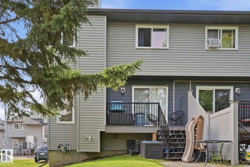 Rear exterior featuring horizontal siding, a deck with black metal railing, and a ground-level patio - 5340 38A Avenue Nw, Edmonton, AB 