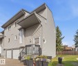 Multi-level exterior with horizontal siding, two integrated garage doors, an elevated entrance with black metal railings, and a prominent front bay window - 5340 38A Avenue Nw, Edmonton, AB 