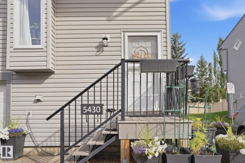 Siding exterior with a bay window, a prominent entry door, and a private entrance with a black metal railing - 5340 38A Avenue Nw, Edmonton, AB 