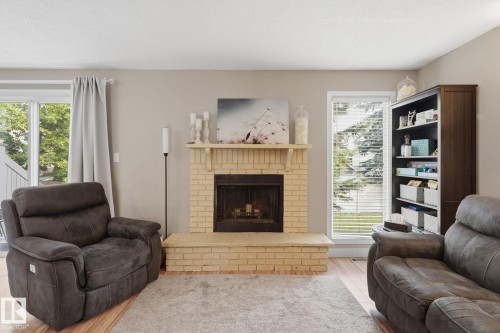 Brick fireplace with hearth, wood-finish flooring, glass sliding door, and a built-in bookcase - 5340 38A Avenue Nw, Edmonton, AB 