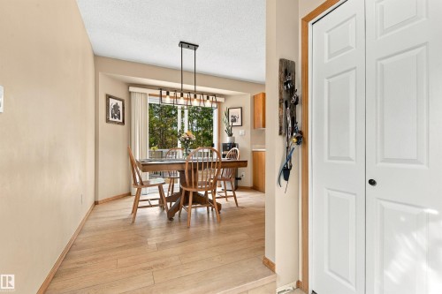 Light wood-finish flooring throughout, bay window with exterior scenery, and a modern rectangular chandelier - 51064 Rge Rd 222, Rural Strathcona County, AB 