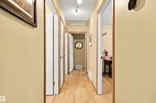 Hallway featuring wood-finish flooring, light-colored walls, and white trim with wood accents - 51064 Rge Rd 222, Rural Strathcona County, AB 