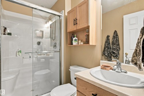 Walk-in shower with sliding glass door, single vanity with integrated sink, and wood-finish cabinetry - 51064 Rge Rd 222, Rural Strathcona County, AB 