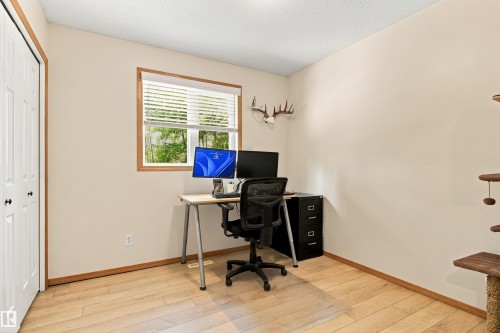 Wood-finish flooring, neutral wall tones, white bi-fold doors, and a window with natural wood trim - 51064 Rge Rd 222, Rural Strathcona County, AB 