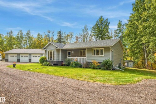 Single-story residence featuring light gray siding, a prominent bay window, and a white railing on the front porch - 51064 Rge Rd 222, Rural Strathcona County, AB 