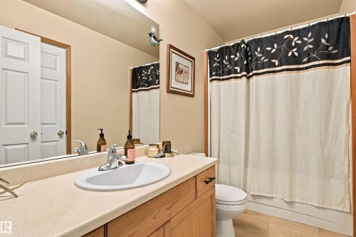 Bathroom featuring an integrated sink, wood-finish vanity, large wall mirror, and a full bathtub with shower - 51064 Rge Rd 222, Rural Strathcona County, AB 