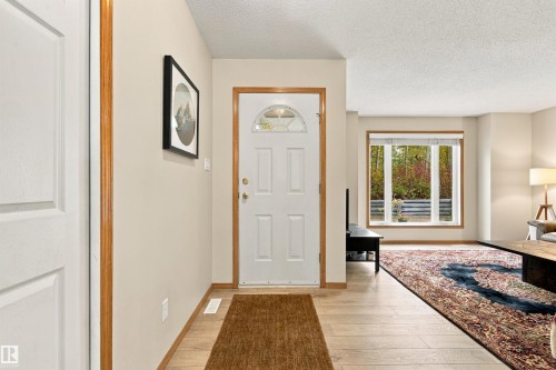 Entryway featuring wood-finish flooring, a paneled door with decorative glass, and wood trim - 51064 Rge Rd 222, Rural Strathcona County, AB 