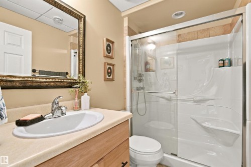 Bathroom featuring a single vanity with an integrated sink, framed mirror, and a shower with a sliding glass door - 51064 Rge Rd 222, Rural Strathcona County, AB 