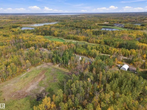 Expansive acreage surrounded by mature trees, featuring a cleared field area and a white Quonset hut - 51064 Rge Rd 222, Rural Strathcona County, AB 