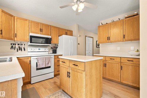 Kitchen featuring light wood-finish cabinetry, white countertops, built-in microwave, and a central island with storage - 51064 Rge Rd 222, Rural Strathcona County, AB 