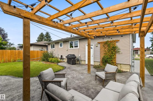 Outdoor space featuring a timber pergola, stamped concrete patio, manicured lawn, wood privacy fencing, and a decorative lattice screen - 6207 85 Avenue Nw, Edmonton, AB 