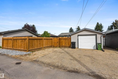 Detached single-car garage with siding exterior, gravel parking pad, and full-height wood fencing - 6207 85 Avenue Nw, Edmonton, AB 