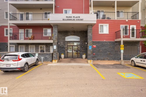 Building entrance with stone accents, a covered portico, and multiple balconies - #416 111 Edwards Dr Sw, Edmonton, AB 