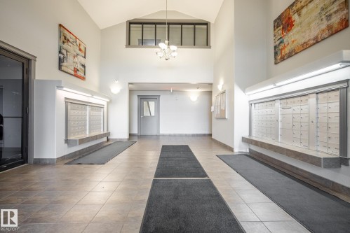 Tiled flooring entrance featuring a vaulted ceiling and integrated mailbox system - #416 111 Edwards Dr Sw, Edmonton, AB 