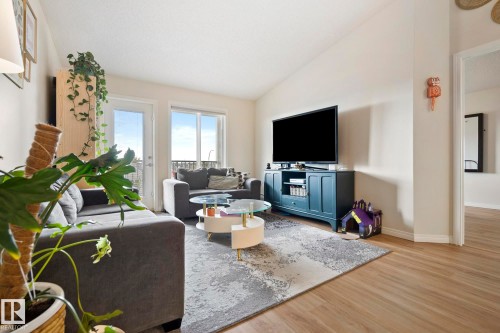 Vaulted ceiling, light wood-finish flooring, sliding glass door, and a light color palette throughout - #416 111 Edwards Dr Sw, Edmonton, AB 