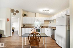 White cabinetry, wood-finish flooring, white appliances, track lighting, and a composite countertop - 