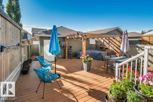 Elevated wood deck featuring an integrated wooden pergola, privacy fencing, and white railing - 6818 Evans Wynd Nw, Edmonton, AB 
