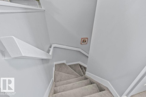 Staircase featuring wall-to-wall carpeting and painted white railings - 6818 Evans Wynd Nw, Edmonton, AB 