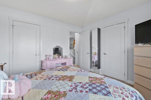 Neutral interior space featuring crisp white wall paint, two-panel shaker-style doors with satin nickel hardware, and an integrated full-length wall mirror - 6818 Evans Wynd Nw, Edmonton, AB 
