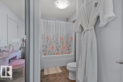 Bathroom featuring a shower-tub combination, ceramic tile flooring, and a flush-mount ceiling light fixture - 6818 Evans Wynd Nw, Edmonton, AB 