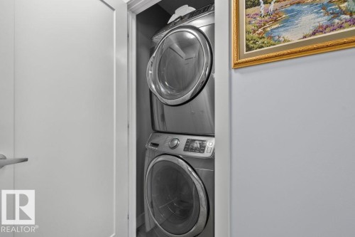 Stacked stainless steel laundry appliances housed within a dedicated closet - 6818 Evans Wynd Nw, Edmonton, AB 