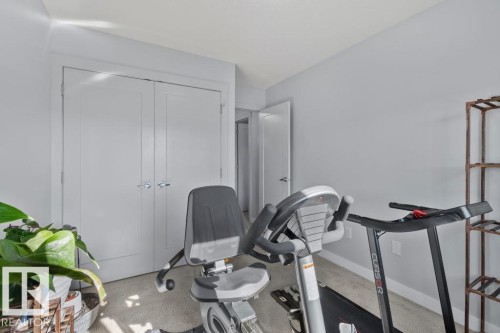 Neutral-toned room featuring light-colored carpet, double-panel doors, and a standard swinging entry door - 6818 Evans Wynd Nw, Edmonton, AB 