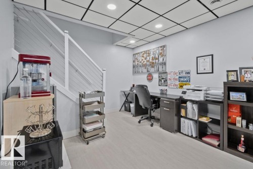 Suspended grid ceiling with recessed lighting, light-toned hard surface flooring, and staircase featuring a white railing with horizontal wire balusters - 6818 Evans Wynd Nw, Edmonton, AB 